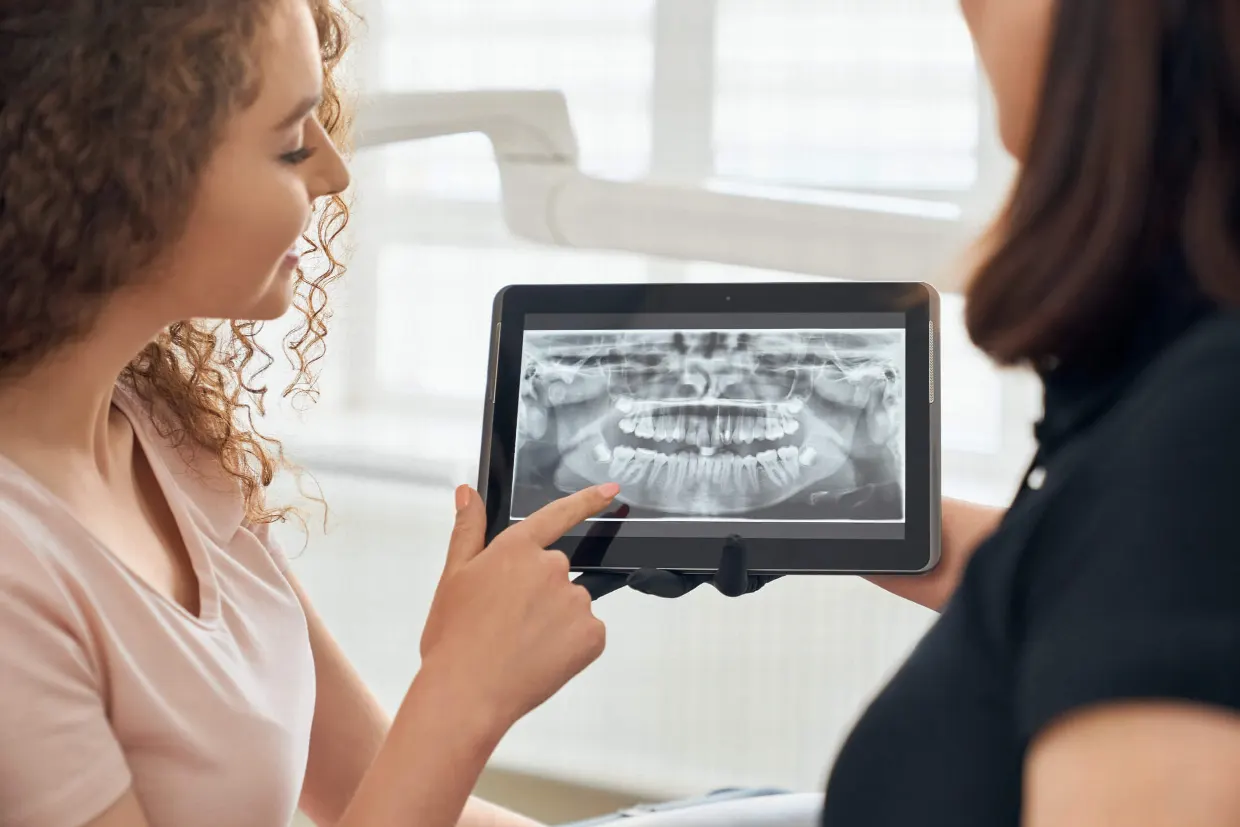 Dentist showing a patient an X-ray before soft and hard tissue surgery