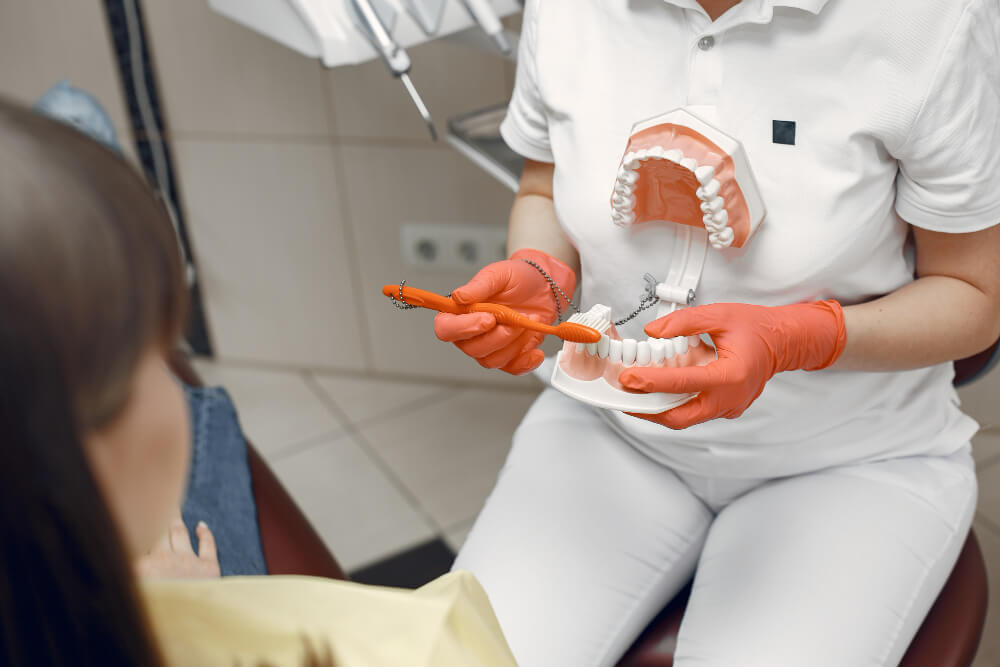 dentálny hygienička ukazuje pacientovi ako si správne čistiť zuby zubnou kefkou